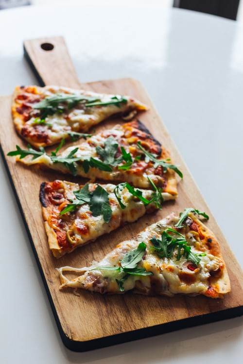 Pizza slices on a wooden board - The Woodfired Co